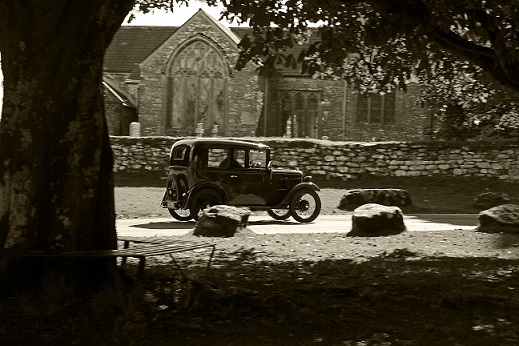 Memories of a bygone era. An Austin 7 passes by Widecombe Church